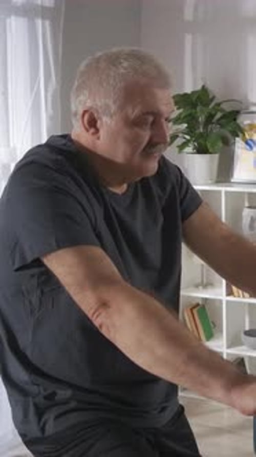 Older Man Exercising Indoors on a Stationary Bike Engaging in Lowimpact Cardio Workout Focusing on