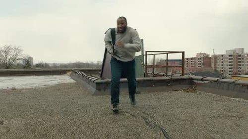 Panting Man Runs Out Through A Door To A Warehouse Rooftop, Catches His Breath And Is Attacked By...