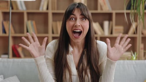 Excited Woman Throws Hands Up in Surprise Indoors