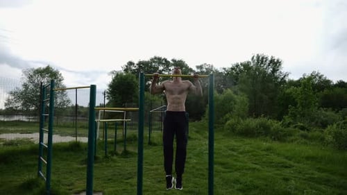 Muscular Athlete Doing Pull Ups on Horizontal Bar at Sports Ground Young Shirtless Sportsman