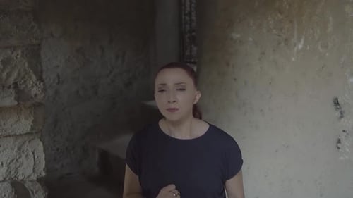 A young woman struggles with herself under the weight of emotions in an old and dark building