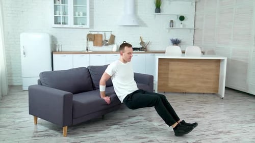 Man Exercising Doing Dips on Sofa Indoors