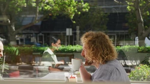 Happy diverse couple drinking coffee and talking at a table in a cafe