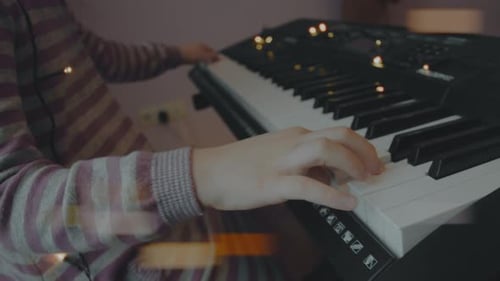 Petite fille jouant du piano électrique lors d'une fête de Noël à la maison Anamorphic Lens Flare