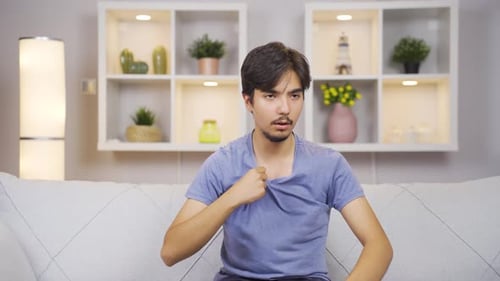 Man Sitting on Couch Feeling Uncomfortably Hot
