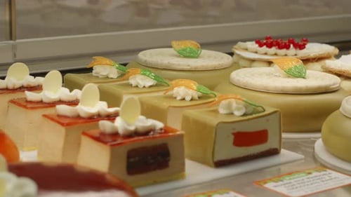 Wide selection of gourmet cakes displayed neatly in a pastry shop showcase.