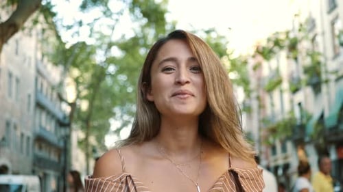 Smiling woman in urban street with green trees