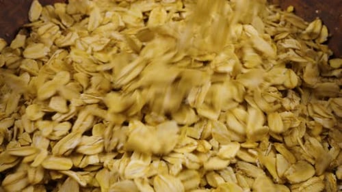 Oatmeal is poured into a terracotta clay bowl. Close-up view.