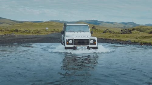 ISLAND — 8. SEPTEMBER 2022: Ein weißer Geländewagen überquert den klaren blauen Fluss.