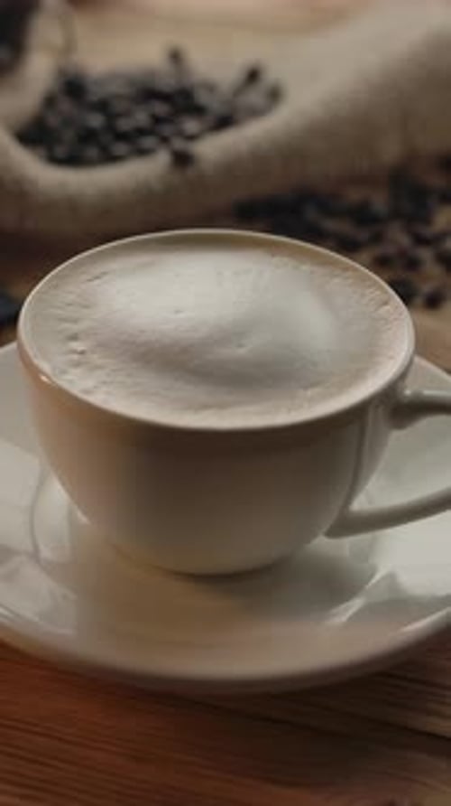 Vertical of Coffee Cup Rotating on Wooden Table
