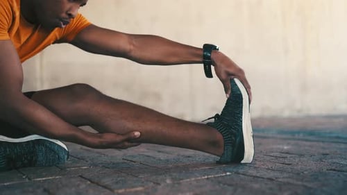 Young Adult Man Stretching Leg in Urban Setting