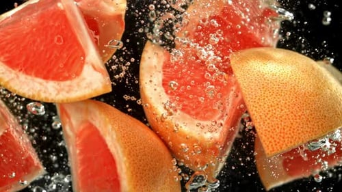 Grapefruit Slices Falling into Water with Bubbles