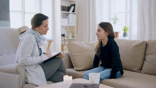 Trauriges und depressives kleines Mädchen spricht drinnen mit einem Therapeuten, Konzept für psychische Gesundheit
