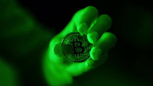 Woman Holding Bitcoin Coin Illuminated by Green Light in Slow Motion Shot