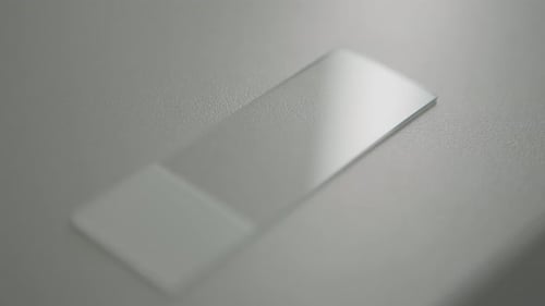 Glass microscope slide on a smooth surface under soft lighting in a close-up shot