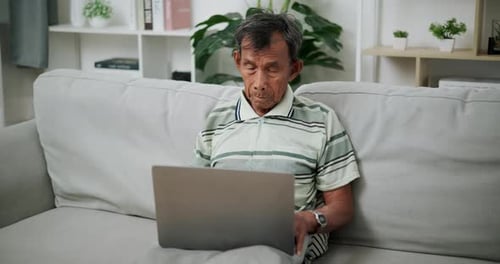 Senior Man Using Laptop on Couch at Home