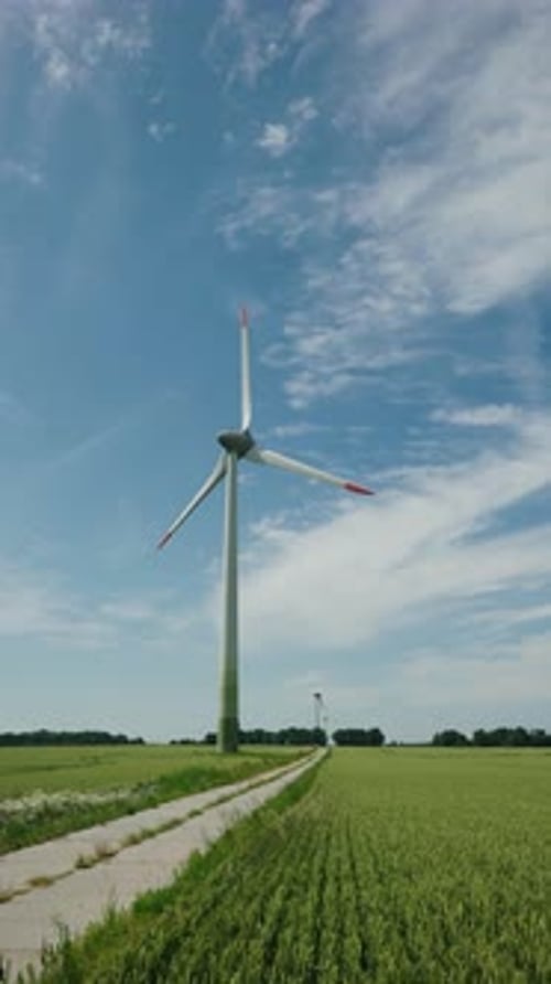Wind Turbine Towering Over Green Fields Under a Bright Blue Sky
