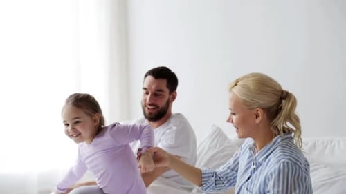 Happy Family Jumps on Bed in Sunny Bedroom