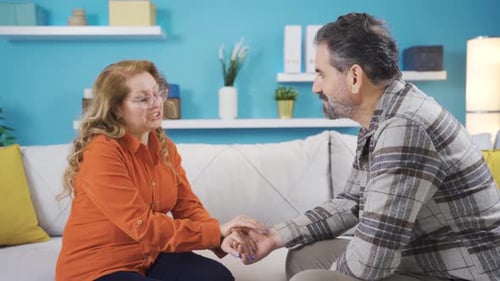 Loving Couple Holding Hands on Sofa