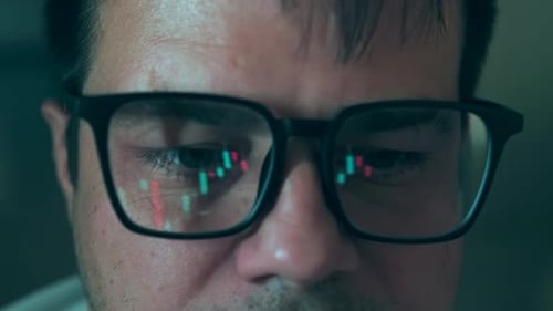 Face caucasian male trader of reflection in eyeglasses stock financial chart background, close up