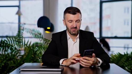 Man in Suit Uses Smartphone in Modern Office