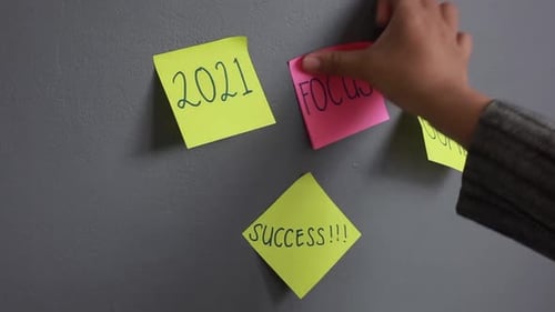 Hand of woman pasting sticky notes for business planning in 2021, concept of new year planning and m