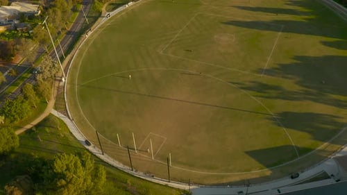 Mehrere Personengruppen nutzen den leeren Sportplatz, um die Nachmittagssonne zu genießen.