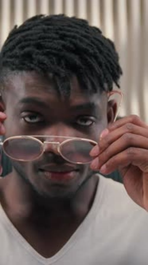 Stylish Fashionable Serious African American Man Putting on Glasses in White Futurism Studio