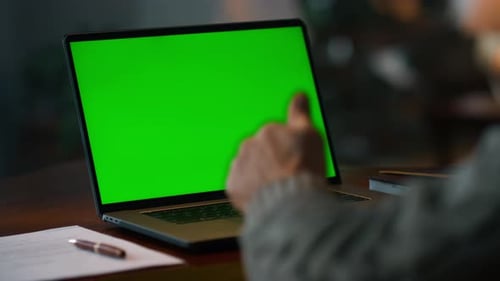 Senior man having video call on green screen laptop at home close up