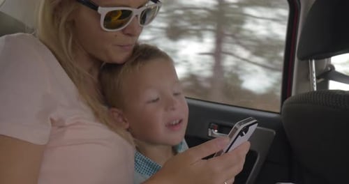 Mother and Son Ride in Car with Phone