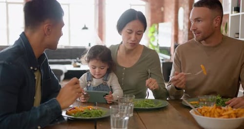 Família extensa comendo refeições saudáveis em casa, criança assistindo entretenimento no telefone
