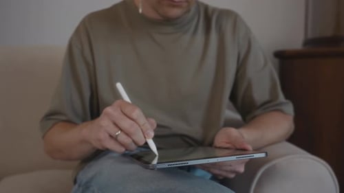 Man Using Stylus on Tablet Device on Couch