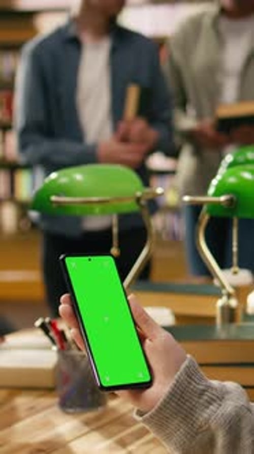 Vertical Video Vertical Chroma Key Editable Screen on Smartphone Held By Person at Library