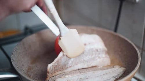 Woman pirien fish in a pan at home. close-up. homemade fish grill