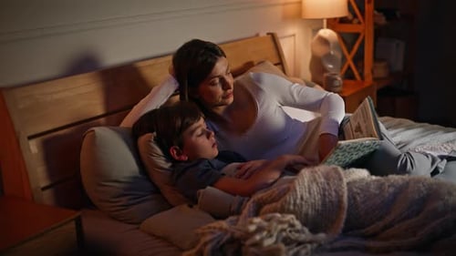 Woman Reads Bedtime Story to Child in Bed