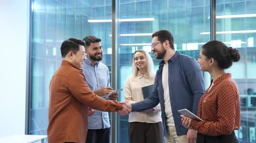 Business people shaking hands after deal at meeting while standing in modern office. Businessmen