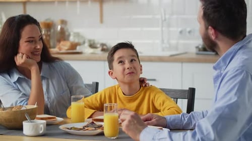 Family Having Cheerful Breakfast Conversation in Kitchen