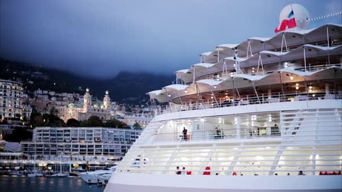 Boats docked in the Monaco Marina with the skyline of the city on the background in the evening