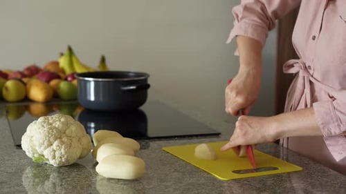 Woman cuts potatoes in her kitchen