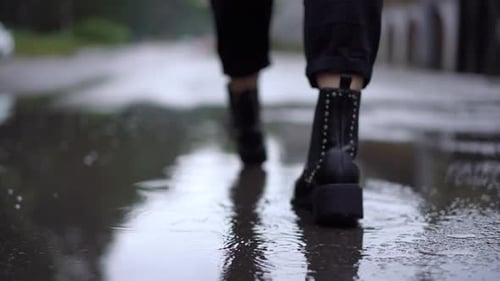 Back View Closeup Unrecognizable Caucasian Woman Walking in Puddles on Overcast Day Tracking Shot of