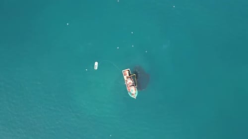 A bird's-eye perspective of a fishing boat as it retrieves its fishing net, securing a rich bounty o