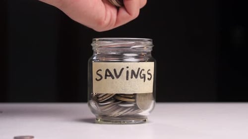 Closeup of Coins Pouring Into a Piggy Bank on a Black Background