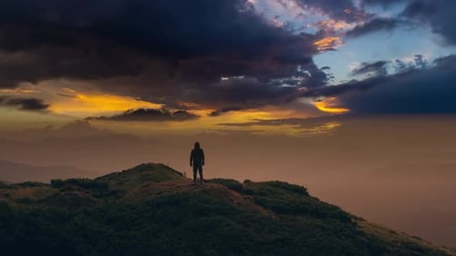 Der Mann, der auf einem Berg vor einem malerischen Wolkenbach steht