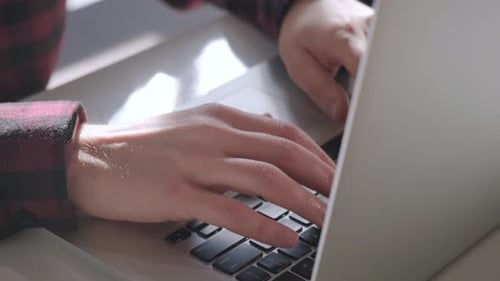 Close up of man hands typing on laptop while working in cafe