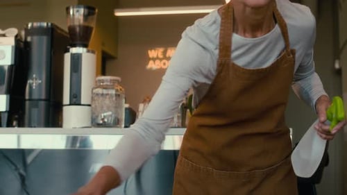 Mature Waitress Cleaning Cafe Tables