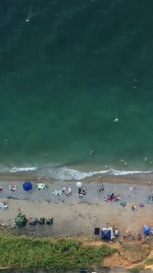 Zeitrafferaufnahme aus der Luft über den Sandstrand bei Sonnenuntergang Im Sommer entspannen sich viele glückliche Menschen am Blau