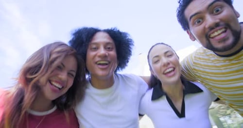 Verschiedene Freunde lehnen sich in die niedrige Handkamera, lachen, telefonieren und teilen Spaß im Freien