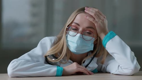 Exhausted Woman Doctor with Face Mask Rests Head