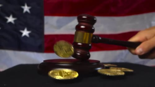 Justice court hammer slammed on table and Bitcoin cryptocurrency coins flying around, US flag also.