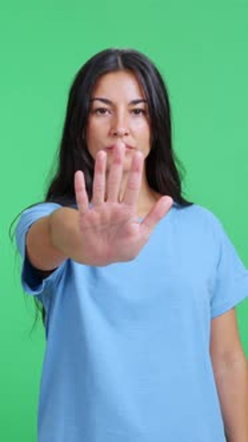 Woman Gesturing Stop Sign with Hand on Green Screen